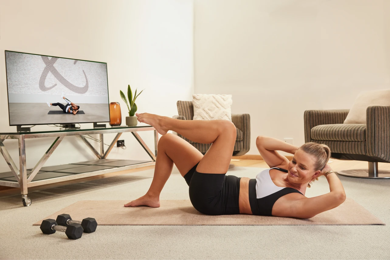 A person laying on the ground following ab excersises coming from the T.V.